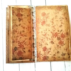 May include: A vintage-style journal with a floral pattern on the cover. The journal has a brown and gold color scheme and a decorative spine.