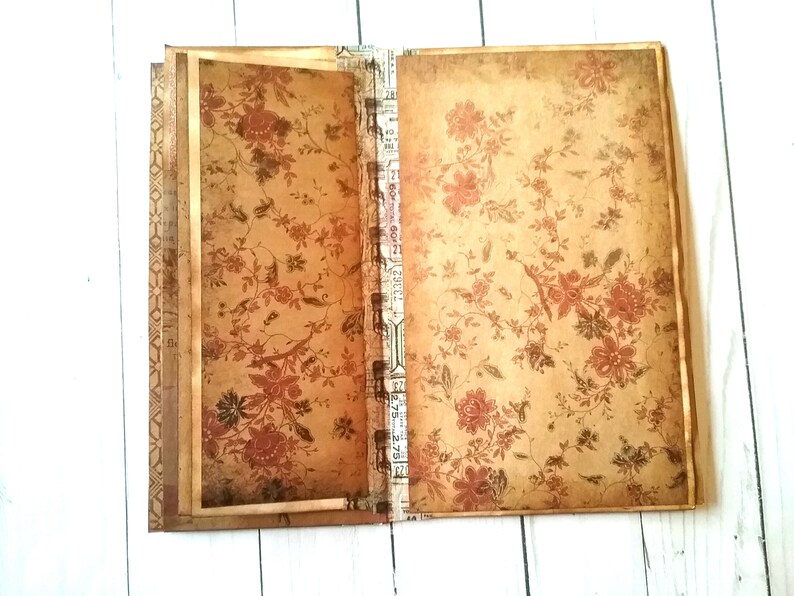 May include: A vintage-style journal with a floral pattern on the cover. The journal has a brown and gold color scheme and a decorative spine.