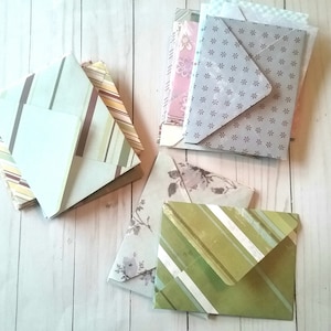 May include: A stack of patterned envelopes in various colors, including green, brown, pink, and gray. The envelopes have different designs, including stripes, floral patterns, and polka dots.
