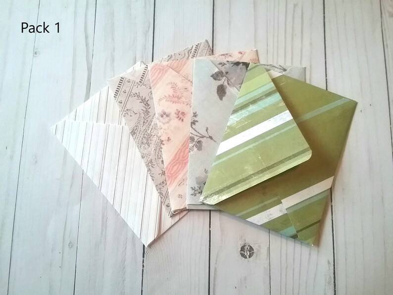 May include: Pack of six patterned envelopes in various colors and designs, including stripes, floral, and paisley. The envelopes are arranged in a fan shape on a white wooden surface. The text "Pack 1" is visible in the top left corner of the image.