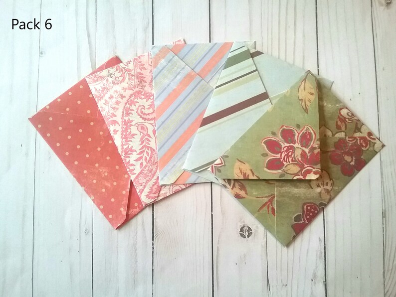 May include: Pack of six decorative envelopes with various patterns. The envelopes are in shades of pink, green, and brown with floral and geometric designs. The text "Pack 6" is visible in the top left corner of the image.