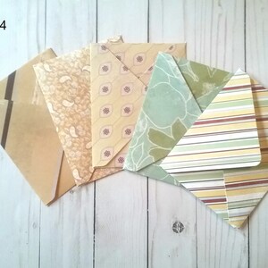 May include: Pack of four patterned envelopes in various shades of green, yellow, and brown. The envelopes have different patterns, including stripes, paisley, and floral designs. The text "Pack 4" is visible in the top left corner of the image.