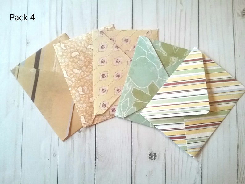 May include: Pack of four patterned envelopes in various shades of green, yellow, and brown. The envelopes have different patterns, including stripes, paisley, and floral designs. The text "Pack 4" is visible in the top left corner of the image.