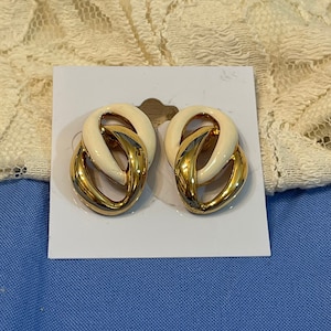 Puede incluir: Un par de pendientes de clip de oro y blanco. Los pendientes tienen forma de nudo retorcido.