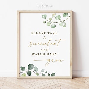 May include: A white sign with a gold frame and green watercolor leaves. The sign says "Please take a succulent and watch baby grow."