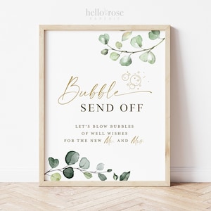 May include: A framed wedding sign with the words "Bubble Send Off" in gold script. The sign includes the text "Let's blow bubbles of well wishes for the new Mr. and Mrs." and is decorated with watercolor eucalyptus leaves.
