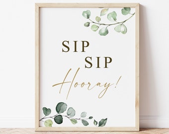 May include: A printable sign with a white background and a wooden frame. The sign features a green eucalyptus leaf design and the text "SIP SIP Hooray!" in black and gold lettering.