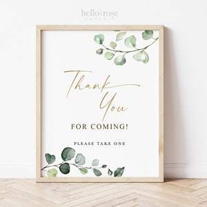 May include: A white sign with a gold "Thank You for Coming!" message and green watercolor eucalyptus leaves. The sign says "Please take one" at the bottom.