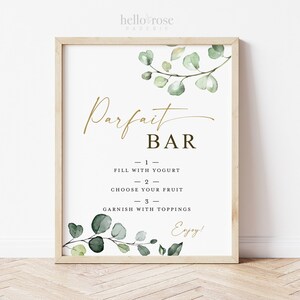 Puede incluir: Un cartel imprimible con un diseño de eucalipto acuarela verde y texto dorado que dice "Parfait Bar". El cartel incluye instrucciones para crear un parfait: "Rellenar con yogur", "Elegir tu fruta" y "Adornar con ingredientes".