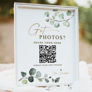 May include: A white rectangular sign in a light-colored frame featuring green watercolor eucalyptus branches. The text reads Got PHOTOS? SHARE THEM HERE, includes a black QR code, and the text SIMPLY SCAN AND UPLOAD with Chloe + Christopher.