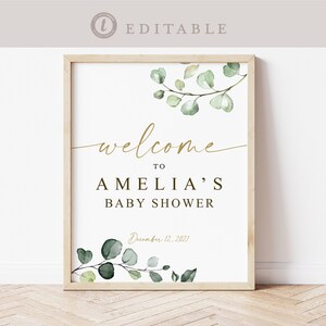 Puede incluir: Un cartel de bienvenida imprimible para un baby shower con un dise&ntilde;o de eucalipto acuarela verde. El cartel dice "Bienvenido a la fiesta de bienvenida de Amelia, 12 de diciembre de 2021".