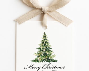 May include: A white gift tag with a watercolor illustration of a green Christmas tree and the words "Merry Christmas" in elegant script. A beige ribbon is tied at the top.