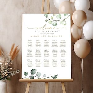May include: A white wedding seating chart with a green eucalyptus branch design. The chart lists tables 1 through 15 with guest names. The text at the top reads "Welcome to our wedding, February 12, 20XX, Micah and Caroline."