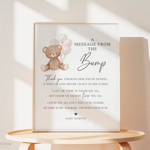 Può includere: Un cartello stampabile con un orsacchiotto marrone che tiene dei palloncini. Il cartello recita "Un messaggio dalla pancia" e include un messaggio del bambino per gli ospiti di un baby shower.