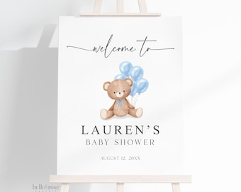 Op de afbeelding: Een babyborrelbord op een ezel. Het bord toont een aquarel illustratie van een teddybeer met blauwe ballonnen. De tekst luidt "welcome to", "LAUREN'S BABY SHOWER" en de datum.