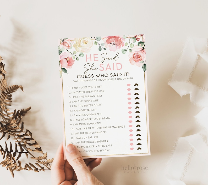 May include: A pink and white floral themed printable game card with the text "He Said She Said Guess Who Said It! Was it the bride or groom? Circle one or both."  The card has a list of 13 questions about the bride and groom, with a pink circle and a brown mustache next to each question.