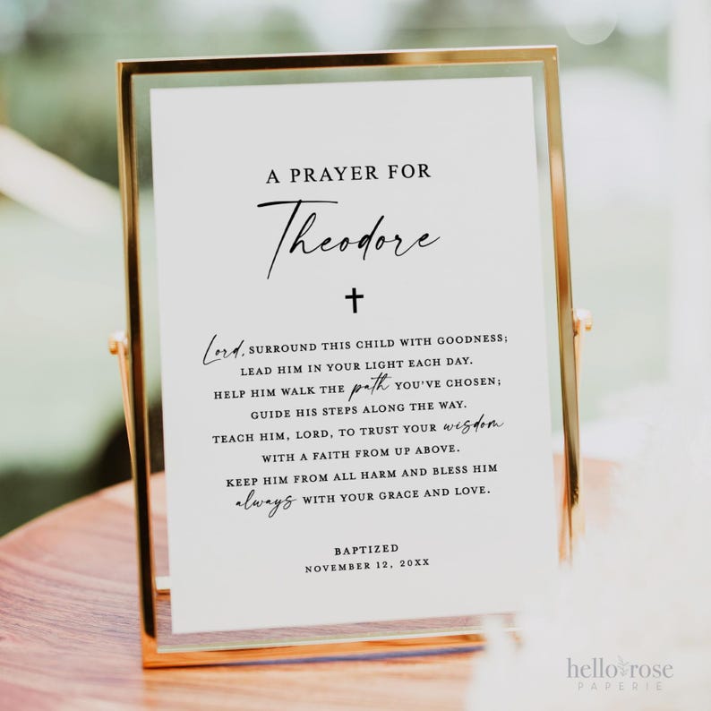 May include: A white framed sign with a black cross at the top and the text "A Prayer for Theodore" in black cursive. The sign includes a prayer for the child, with the text "Baptized November 12, 20XX" at the bottom.