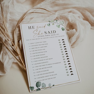 May include: A white card with a gold border and green foliage design. The card has the text "He said She Said" and a list of 15 questions about a couple's relationship.  The card is designed for a wedding shower or bridal party game.