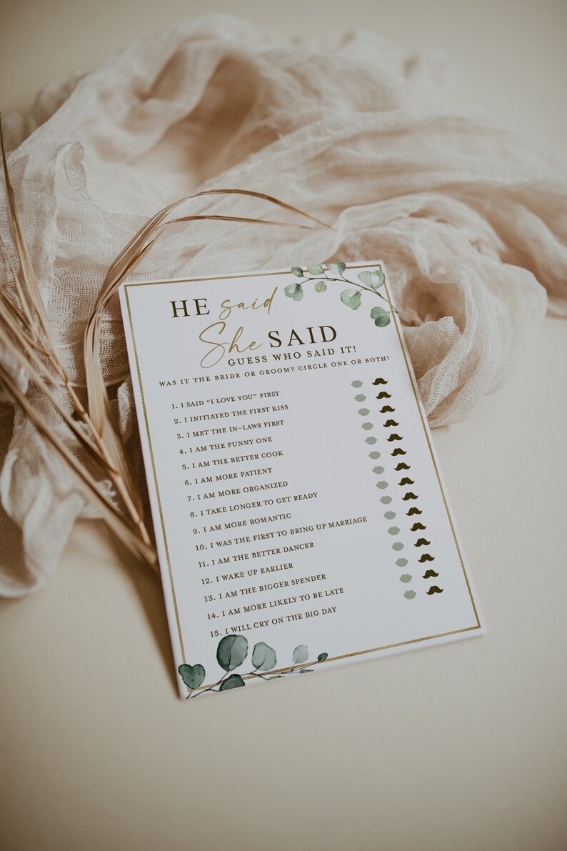 May include: A white card with a gold border and green foliage design. The card has the text "He said She Said" and a list of 15 questions about a couple's relationship.  The card is designed for a wedding shower or bridal party game.