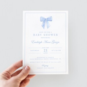 May include: A baby shower invitation with a light blue bow illustration at the top. The invitation includes the text "Join us for a Baby Shower Honoring Emileigh Anne Garza". Details include the date, time, and location.