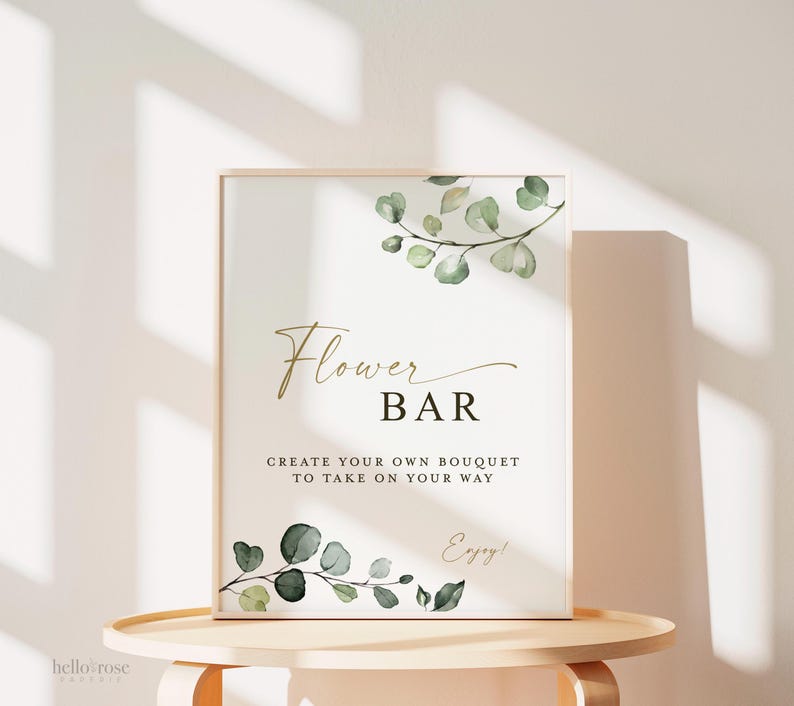 Pode incluir: Uma placa retangular numa moldura de madeira clara com ilustra&ccedil;&otilde;es de folhas de eucalipto verdes no topo e na base. O texto diz Flower BAR, CREATE YOUR OWN BOUQUET TO TAKE ON YOUR WAY e Enjoy! em letras douradas e pretas.