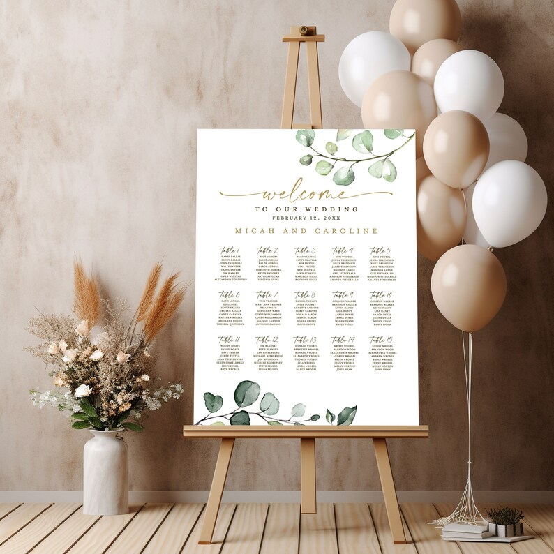May include: A white wedding seating chart with a green eucalyptus branch design. The chart lists tables 1 through 15 with guest names. The text at the top reads "Welcome to our wedding, February 12, 20XX, Micah and Caroline."