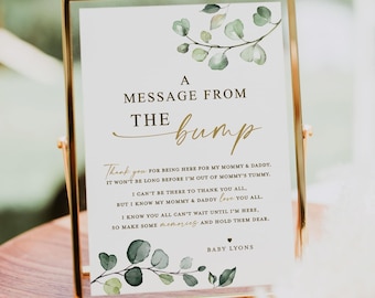 Puede incluir: Un cartel blanco con texto dorado y hojas verdes de acuarela dice "A Message From The Bump". El texto continúa con un mensaje del bebé a los invitados de la fiesta de bienvenida al bebé. El cartel dice "Gracias por estar aquí para mi mamá y mi papá. No pasará mucho tiempo antes de que salga del vientre de mi mamá. No puedo estar allí para agradecerles a todos, pero sé que mi mamá y mi papá los quieren a todos. Sé que todos ustedes no pueden esperar a que esté aquí, así que hagan algunos recuerdos y guárdenlos para siempre. Bebé Lyons."