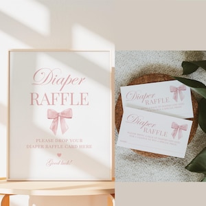 May include: A pink and white sign with the text "Diaper Raffle" and a pink bow. The sign says "Please drop your diaper raffle card here. Good luck!"