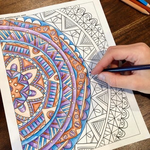 May include: A detailed mandala coloring page with intricate patterns in shades of blue, purple, and brown. The page is partially colored in with colored pencils, showing the progress of the coloring process.