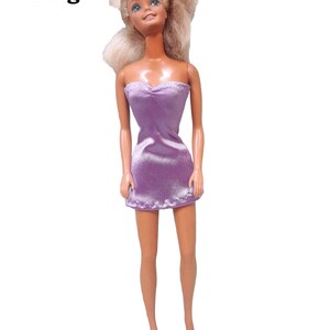 May include: A vintage Barbie doll with blonde hair wearing a purple strapless dress made from satin finish charmeuse spandex.