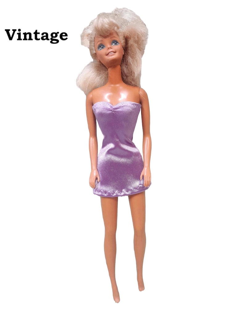 May include: A vintage Barbie doll with blonde hair wearing a purple strapless dress made from satin finish charmeuse spandex.