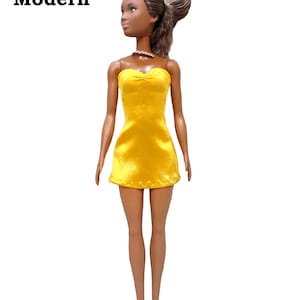 May include: A doll wearing a yellow strapless dress made from satin finish charmeuse spandex.