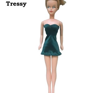 A doll wearing a hunter green strapless mini dress made from satin finish charmeuse spandex.