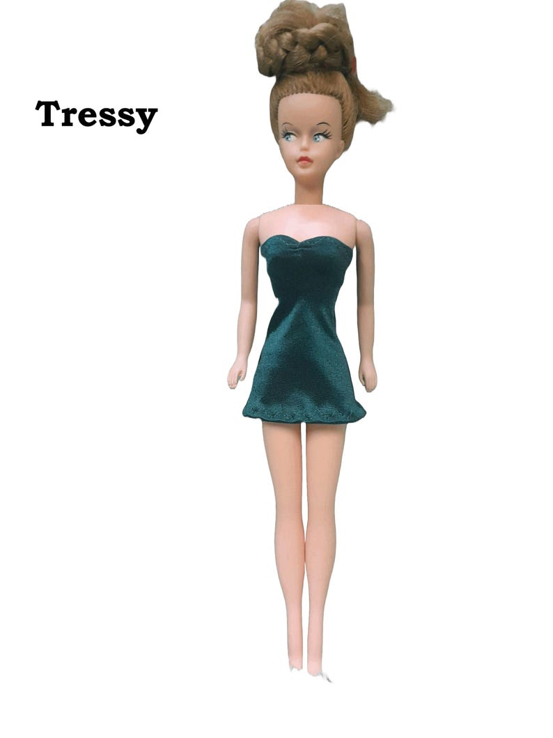 A doll wearing a hunter green strapless mini dress made from satin finish charmeuse spandex.