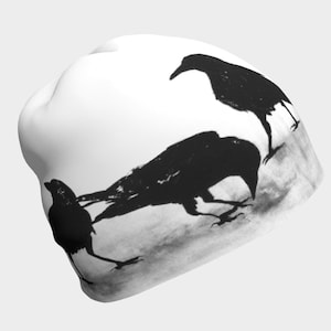 May include: White beanie with a black and white silhouette of three crows on a white background.
