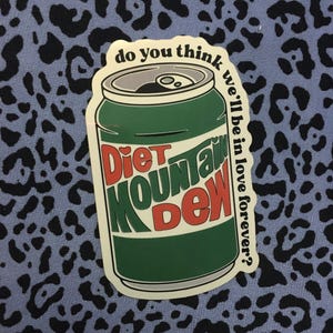 May include: A sticker featuring a green Diet Mountain Dew can with red and white text. The can is labeled "Diet Mountain Dew" and has the phrase "do you think we'll be in love forever?" printed on the side.