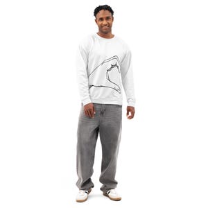 May include: White sweatshirt with a black hand gesture graphic. The sweatshirt is paired with gray, loose-fitting jeans and white sneakers. The person is standing in front of a white background.