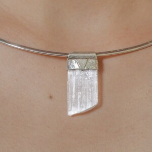 Puede incluir: Un collar choker plateado con un colgante de cristal transparente.