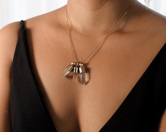 Puede incluir: Un collar de cadena dorada con múltiples colgantes de cristal. El collar lo lleva una persona con una blusa negra.