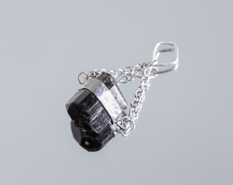 May include: A black tourmaline crystal pendant with a silver chain and a silver band around the crystal.