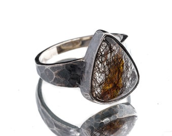 May include: A silver ring with a hammered band and a triangular clear quartz stone with brown inclusions.