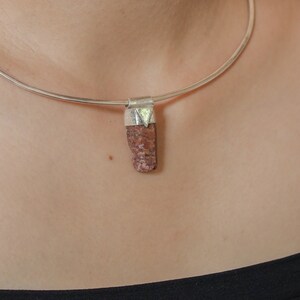 May include: A silver choker necklace with a pendant made of a rough, reddish-brown stone.