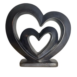 May include: A silver-colored metal sculpture of two interlocking hearts. The hearts are hollow and have a smooth, polished finish.