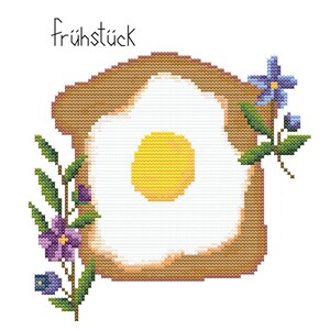 May include: A cross-stitch pattern of a fried egg on toast with a yellow yolk and purple flowers on the side. The text "frühstück" is written above the image.
