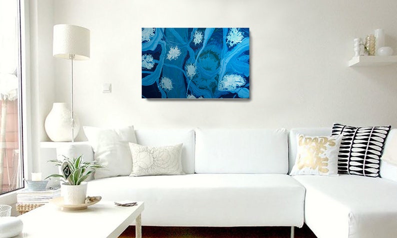 May include: Abstract painting with swirling blue and white patterns. The painting has a textured look and is framed in a white frame.