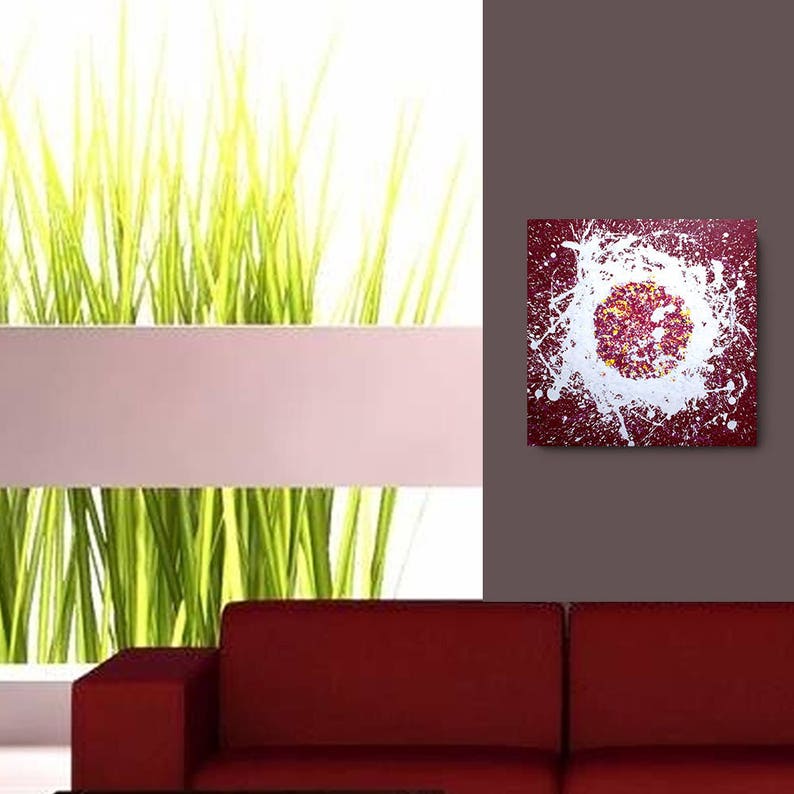 May include: Abstract painting with a white splatter design on a burgundy background. The splatter design creates a circular shape in the centre of the painting.