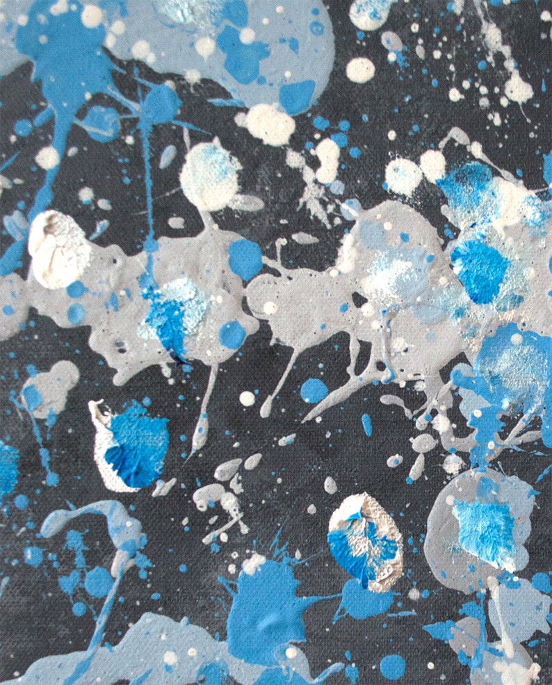 May include: Abstract art painting with blue, white, and gray paint splatters on a black background.