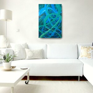 May include: A white sectional sofa with white pillows and a green and blue abstract painting hanging on the wall above it.