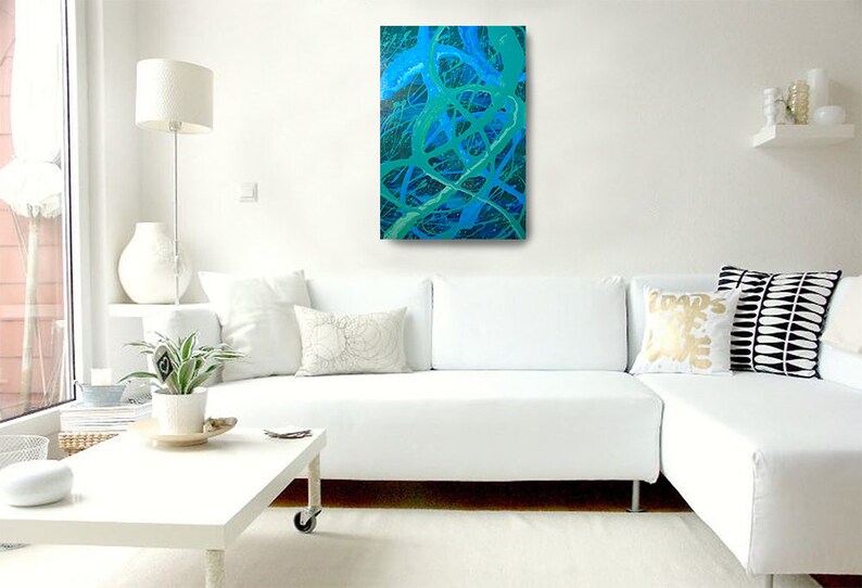 May include: A white sectional sofa with white pillows and a green and blue abstract painting hanging on the wall above it.
