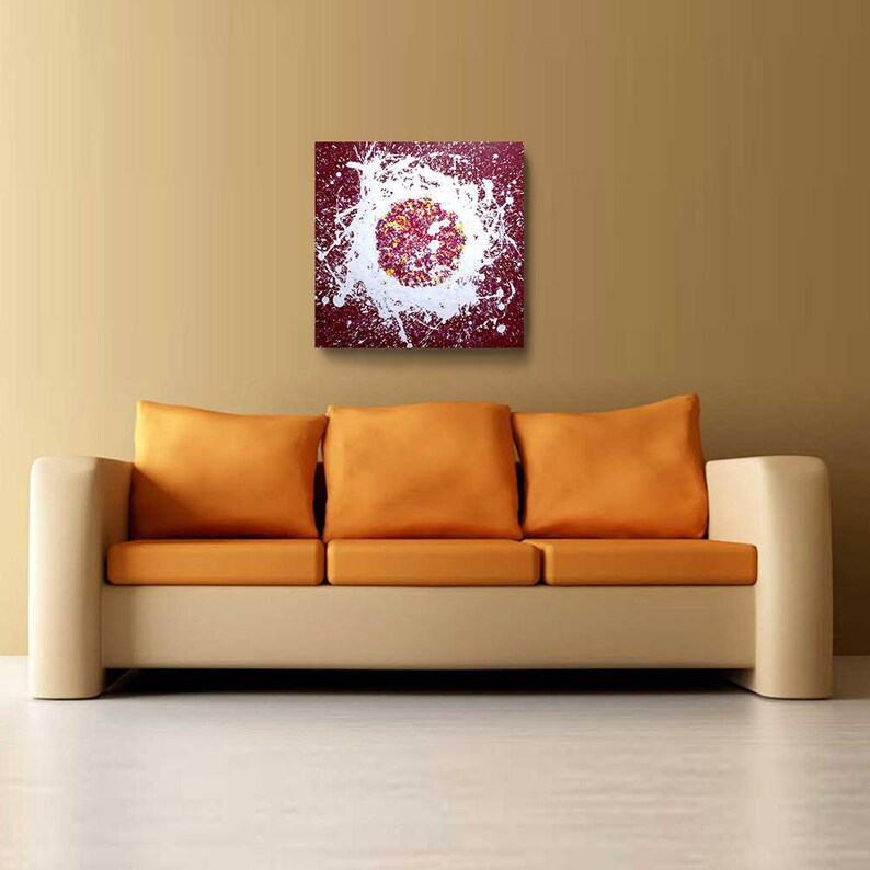 May include: Abstract painting with white splatter paint on a burgundy background. The splatter paint forms a circle in the centre of the canvas.